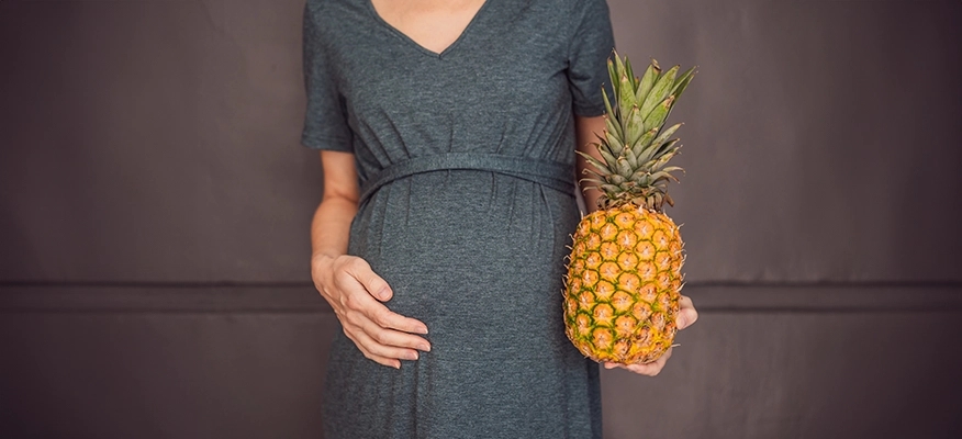 Pregnant woman enjoying a bowl of fresh pineapple, illustrating safe consumption during pregnancy